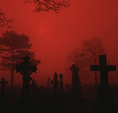 a graveyard with crosses in the foreground and a red sky behind it at night