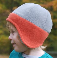 a young child wearing a hat with an orange and grey color block on the front