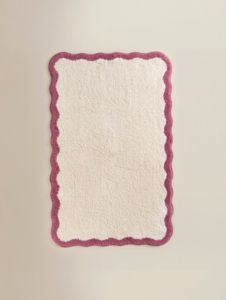 a white rug with pink trim hanging on the wall