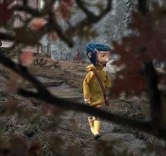 a young boy in yellow raincoat and blue helmet walking on dirt path next to trees