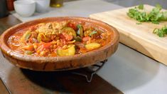 a wooden bowl filled with lots of food next to a cutting board on top of a table