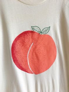 a white t - shirt with an orange on it