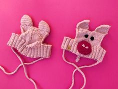 two knitted mittens on a pink background with one wearing a cow's nose