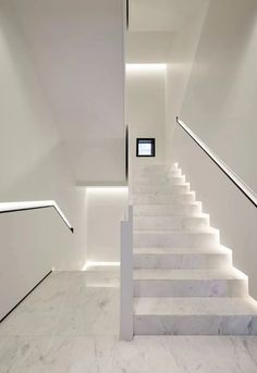 a white staircase leading up to the second floor in a modern house with marble floors and walls