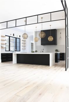 an open kitchen with black cabinets and white counter tops, along with wooden flooring