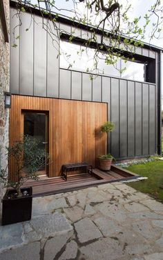 a wooden building with a bench and potted plant on the front lawn area next to it