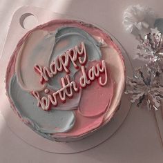 a birthday cake sitting on top of a white plate next to a pink and blue frosted cake