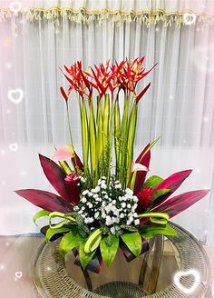 a vase filled with red and white flowers on top of a table next to a window