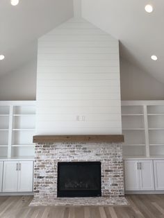 an empty room with a fireplace and built in bookshelves