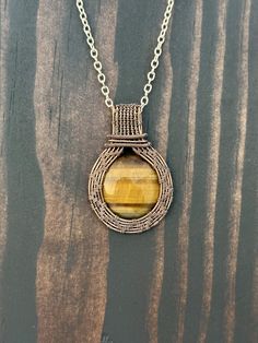 a yellow tiger's eye stone in a wire wrapped pendant on a silver chain