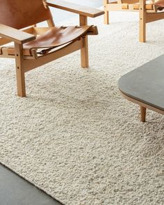 a living room with two chairs and a coffee table on top of a white rug