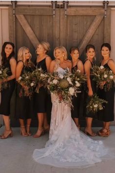 a group of women standing next to each other in front of a wooden door holding bouquets