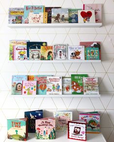 three white shelves with books on them against a tiled wall in a children's room