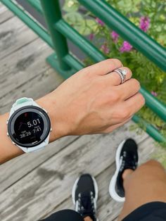 a person is holding onto their watch while standing on a wooden deck with flowers in the background