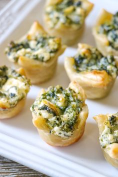 mini quiches with spinach and cheese on a white platter, ready to be eaten