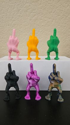 four different colored toy figures sitting on top of a black table next to a wall