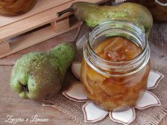 a jar filled with pickles sitting on top of a table next to two pears