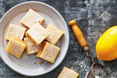 some sugary squares are on a plate next to an orange