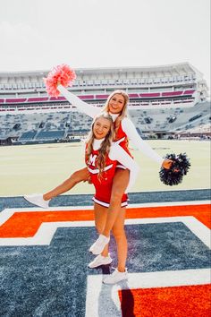 two cheerleaders are posing on the football field