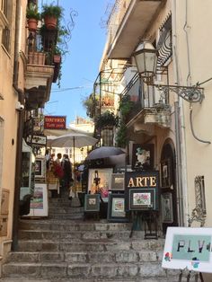 an alleyway with people walking up and down the stairs, some holding umbrellas