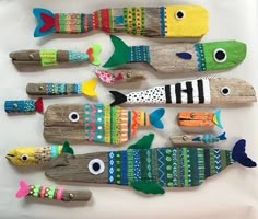 five fish made out of driftwood on a white tray, each with different colors and sizes