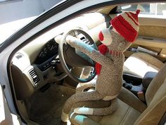 a sock monkey sitting in the driver's seat of a car