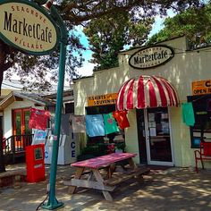 the outside of a market place with tables and umbrellas