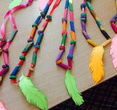 several colorful feathers are laid out on a table with colored sticks attached to the beads