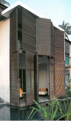 a modern house with wooden slats on the outside and inside, in front of palm trees