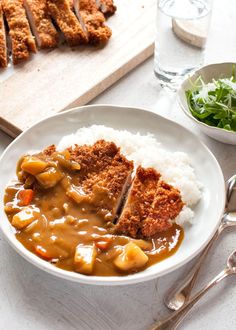 a white bowl filled with meat and gravy on top of rice