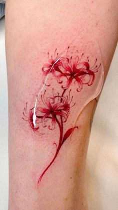 a woman's leg with red ink on it and some flowers in the middle