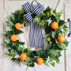 a wreath with oranges and greenery on it