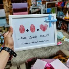 a person holding up a sign with two hearts on it in front of other items