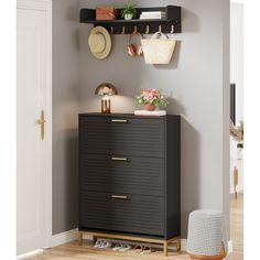 a black dresser in a room with shoes and hats hanging on the wall above it