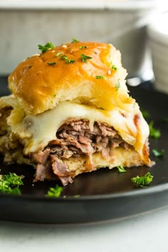 a close up of a sandwich on a plate with meat, cheese and parsley