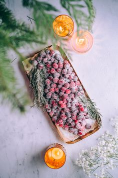 a table topped with candles and a cake covered in frosted balls next to flowers