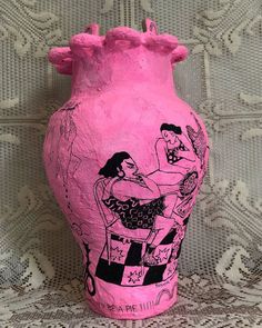 a pink vase sitting on top of a lace tablecloth covered floor next to a wall