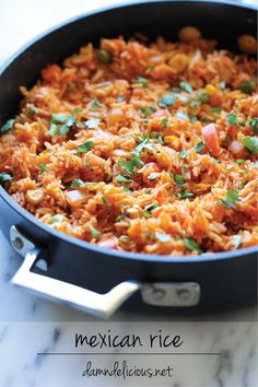 a pan filled with rice and vegetables on top of a stove