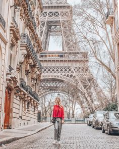 a woman walking down a cobblestone street in front of the eiffel tower