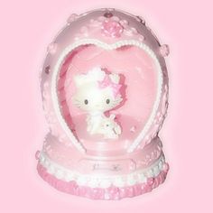 a hello kitty figurine in a pink heart shaped box on a pink background