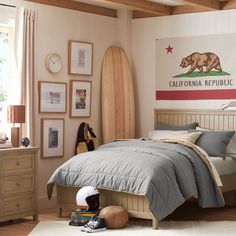 a bed room with a neatly made bed and a surfboard hanging on the wall