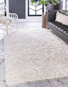 a large white rug in a living room next to a couch and chair with a potted plant