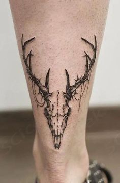 a black and white photo of a deer skull tattoo on the leg, with an antelope's head