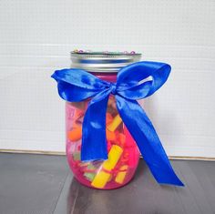 a jar filled with lots of candy sitting on top of a table next to a wall