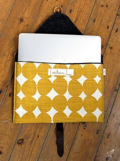 an open laptop computer sitting on top of a yellow and white bag with a name written on it