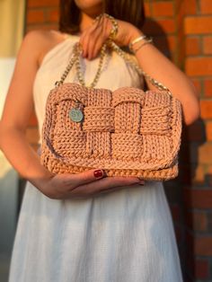 a woman is holding a crocheted purse