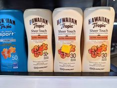 three hawaiian tropic sunscreens are on display in a store shelf with other products