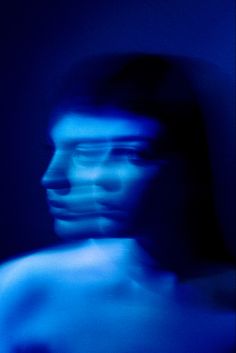 a blurry image of a man's face and torso in blue light,