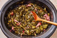 cooked collard greens in a slow cooker with a wooden spoon