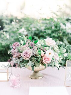 a vase filled with flowers sitting on top of a table next to two small frames